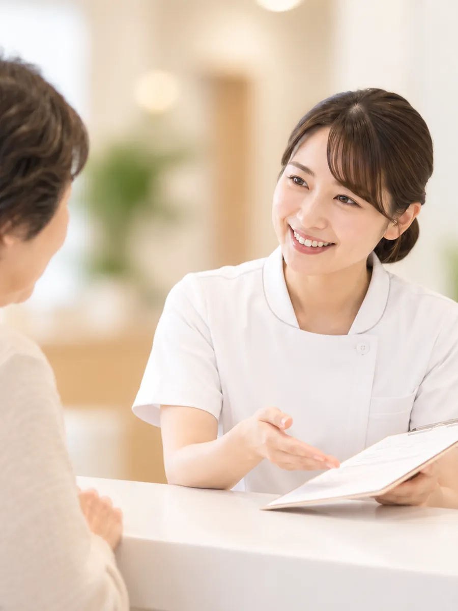 受付で問診票の書き方を案内する倉重病院の看護師